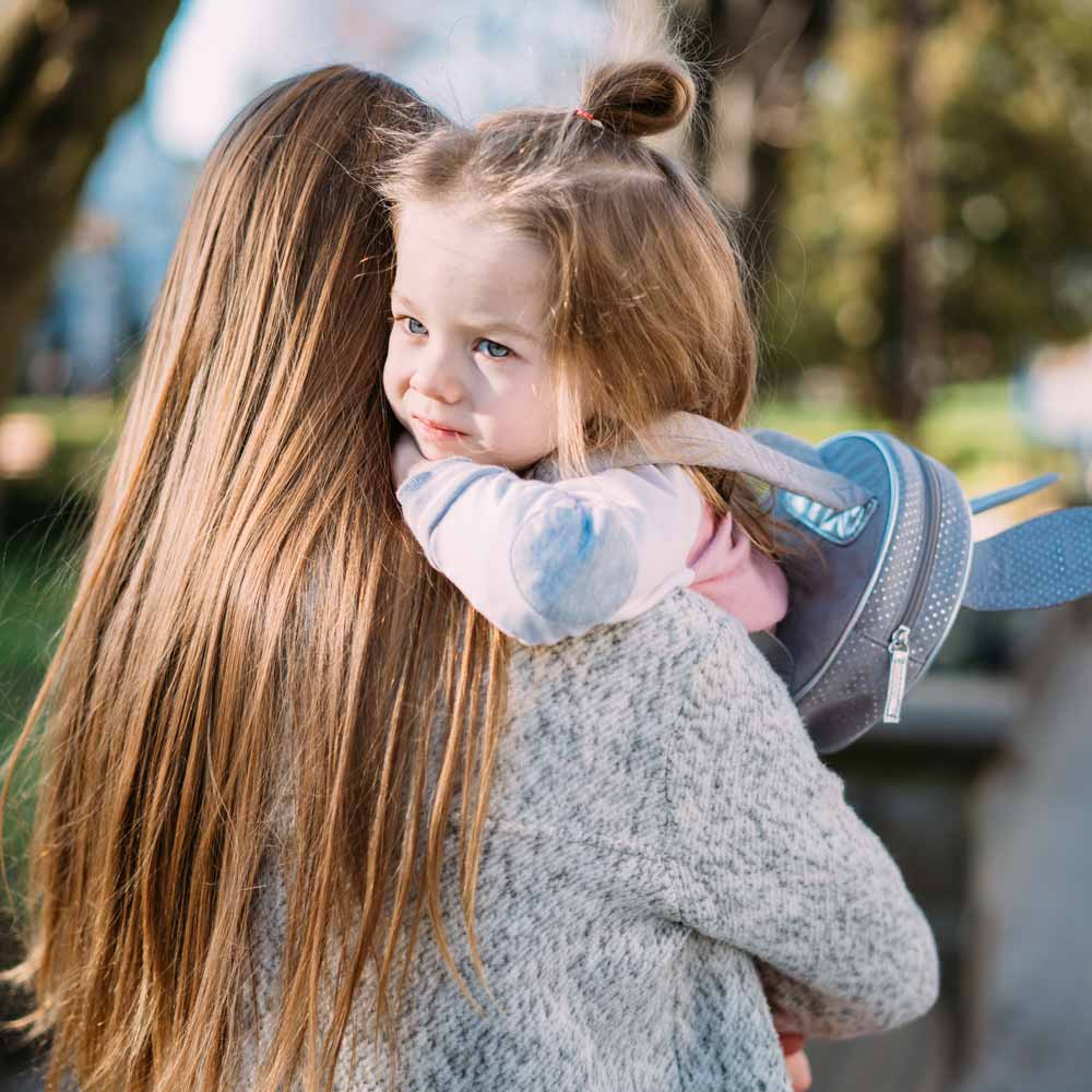 woman holding small girl in her arms with her back turned